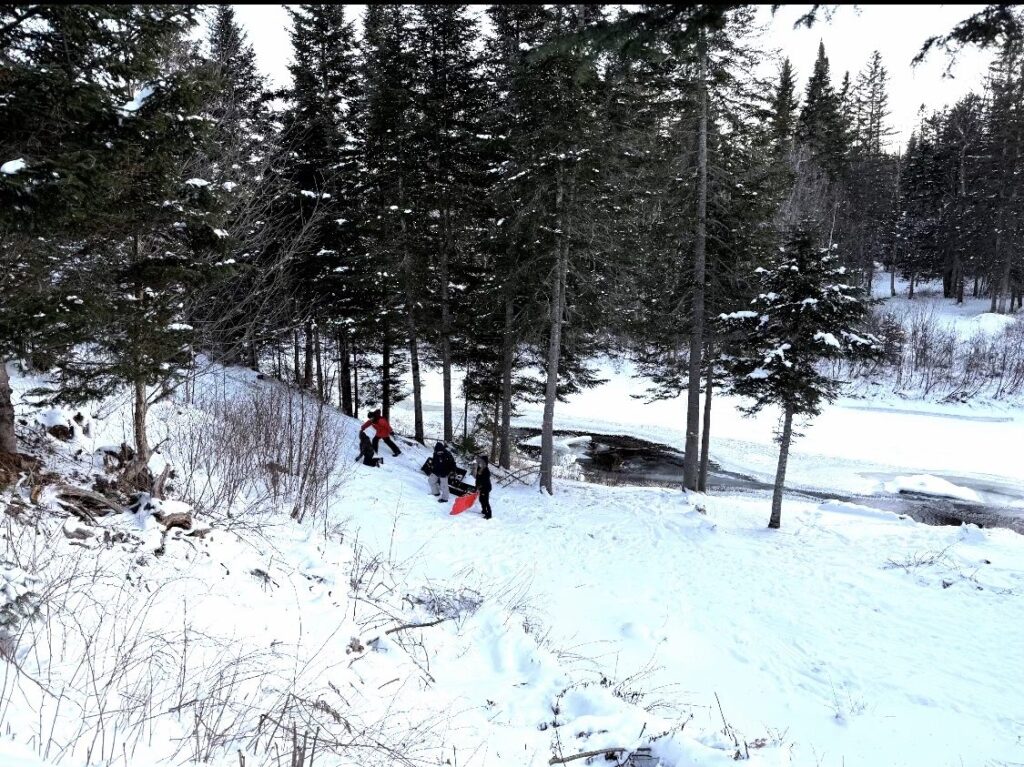 Family sledding through a wooded snowy hillside