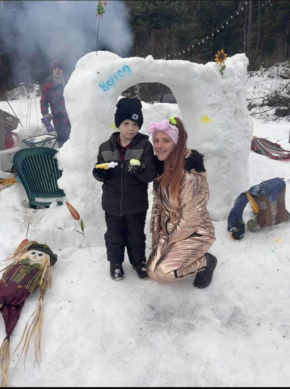 Family members beside their decorated snow igloo in January 2026